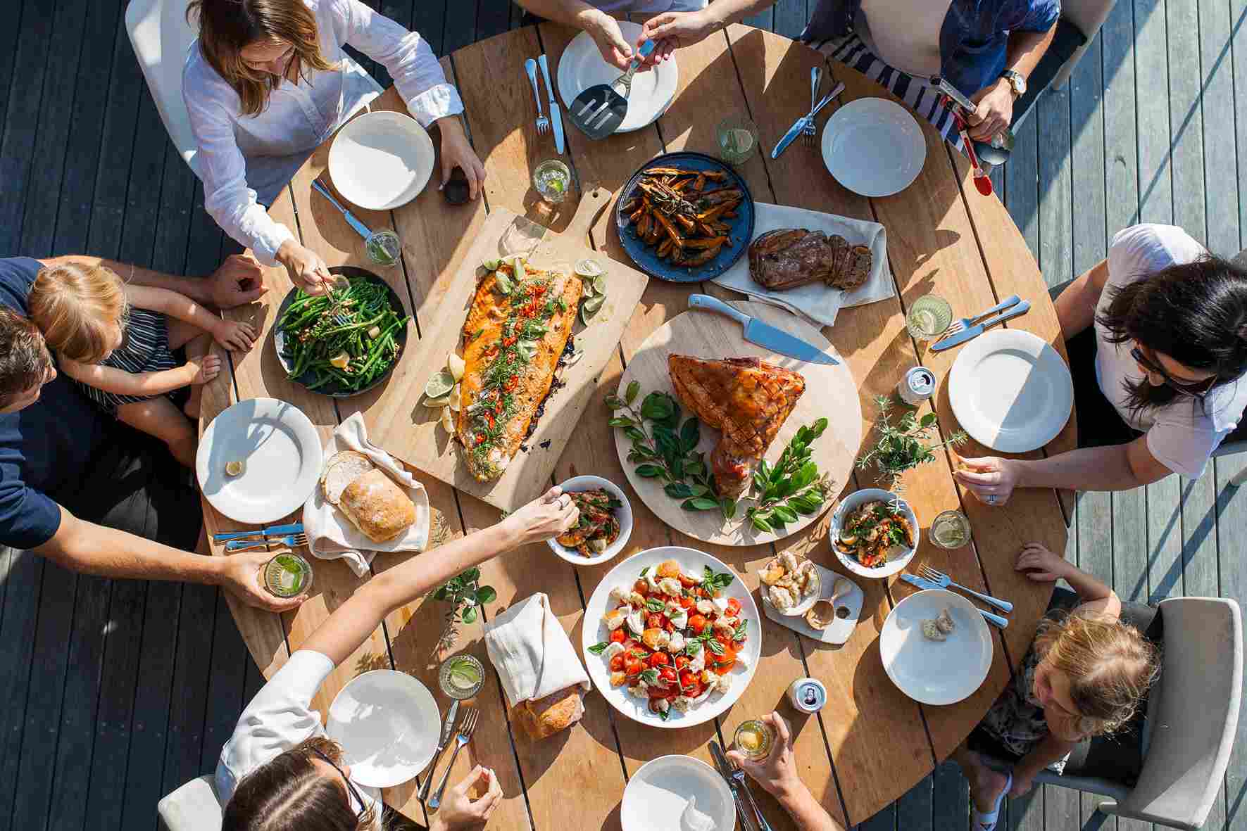 Several people at a convivial meal with a table full of plates of colorful food